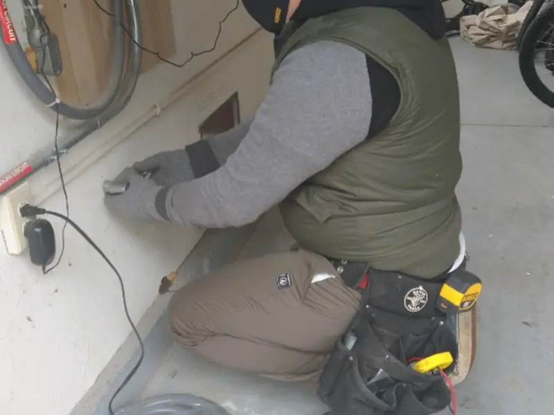 Electrician performing outlet wiring in a Riley garage